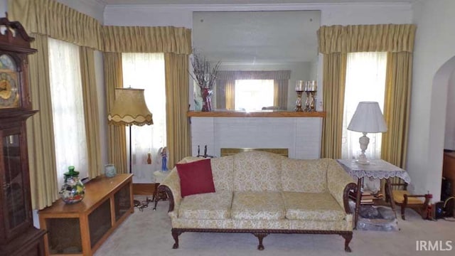 sitting room featuring arched walkways, carpet floors, a fireplace, and ornamental molding
