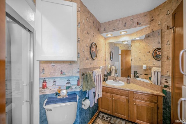 bathroom featuring backsplash, toilet, vanity, and a shower with shower door