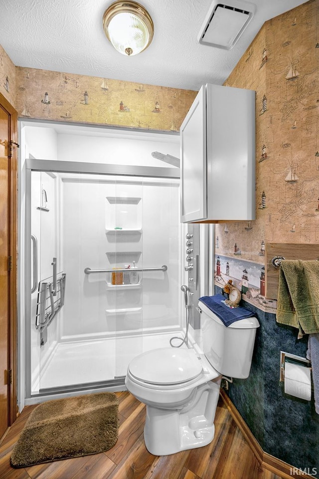 bathroom featuring a shower stall, wood finished floors, visible vents, toilet, and a textured ceiling