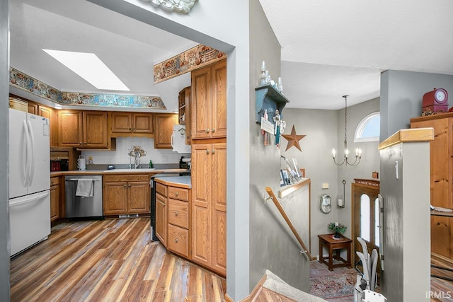 kitchen featuring light countertops, a sink, white appliances, light wood-type flooring, and brown cabinetry