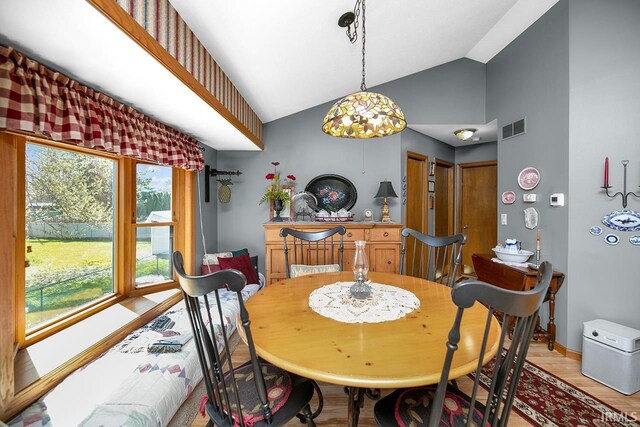 dining space with lofted ceiling, baseboards, visible vents, and light wood finished floors