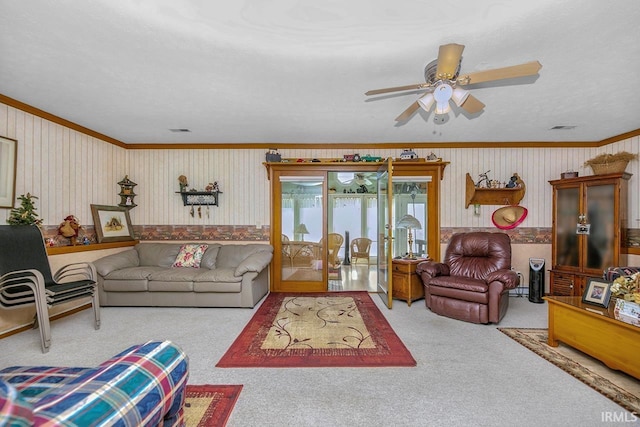 carpeted living room featuring ceiling fan, visible vents, ornamental molding, and wallpapered walls