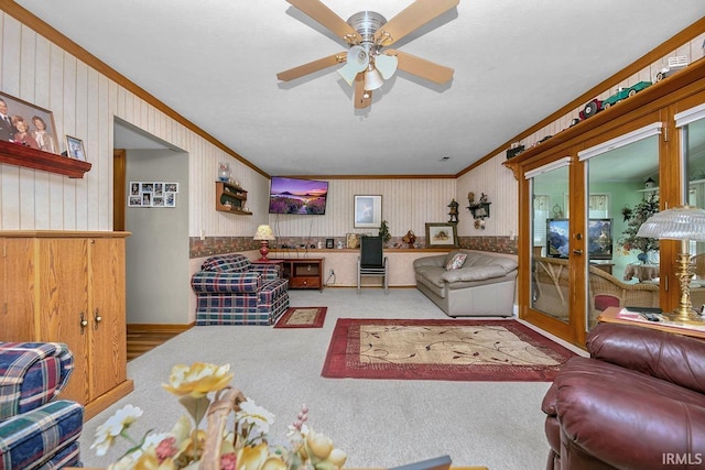 living room with ceiling fan, carpet floors, ornamental molding, and wooden walls