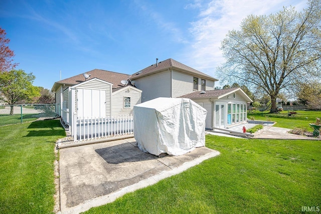 rear view of property featuring a patio area, fence, an outbuilding, a yard, and a storage unit