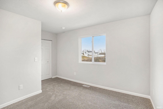carpeted spare room with visible vents and baseboards