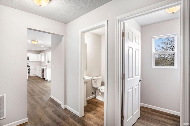 hallway featuring dark wood-type flooring, visible vents, and baseboards