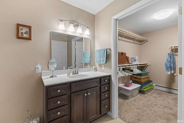 bathroom featuring baseboard heating, vanity, and a spacious closet