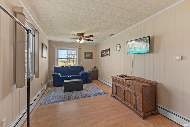 sitting room with light wood-style flooring, crown molding, and baseboard heating