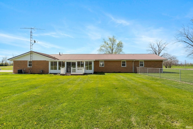 back of house with fence, a lawn, a sunroom, and brick siding