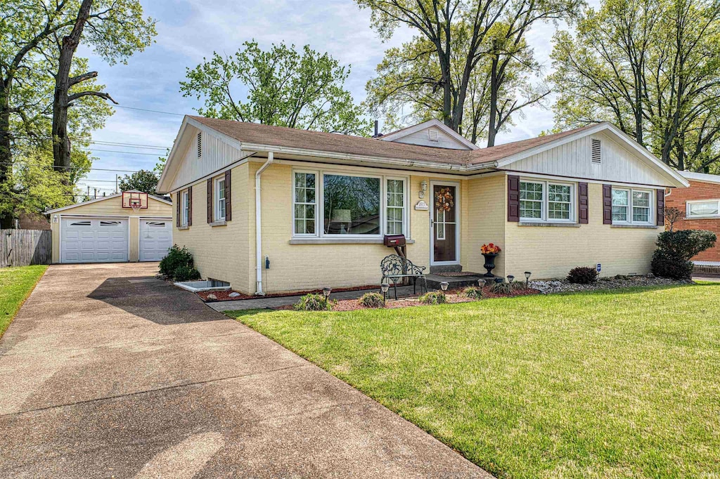 ranch-style home featuring brick siding, a detached garage, an outbuilding, and a front yard