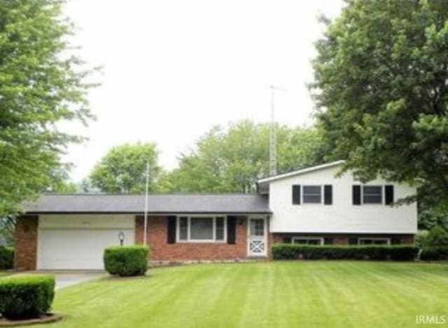 tri-level home featuring brick siding, a front lawn, driveway, and a garage