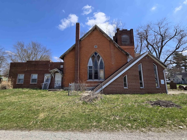 view of front of house with a front lawn, a chimney, and brick siding