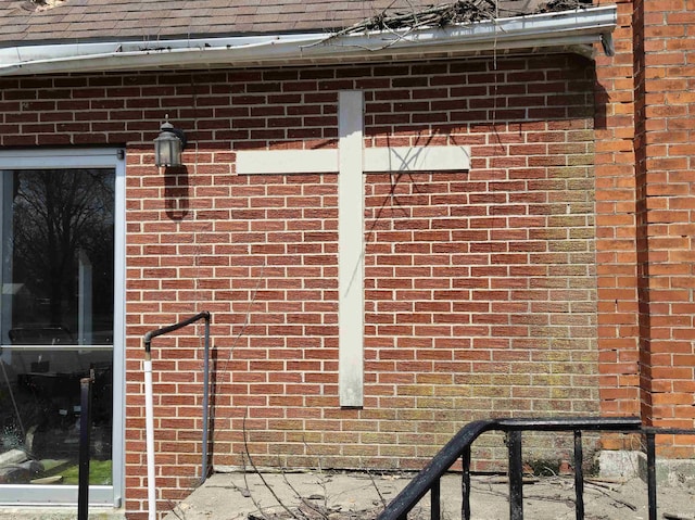details featuring brick siding and roof with shingles
