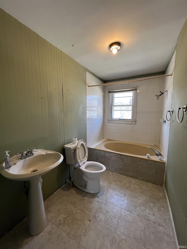 bathroom with tiled shower / bath combo, wood walls, and toilet