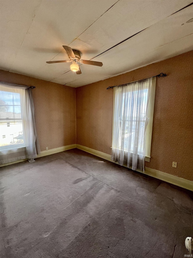 unfurnished room with carpet, a healthy amount of sunlight, a ceiling fan, and baseboards