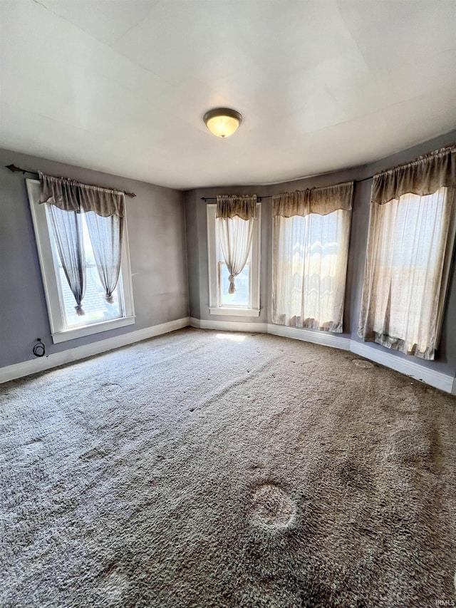 carpeted empty room featuring baseboards