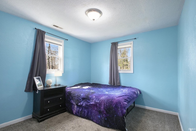 carpeted bedroom featuring a textured ceiling, visible vents, baseboards, and multiple windows