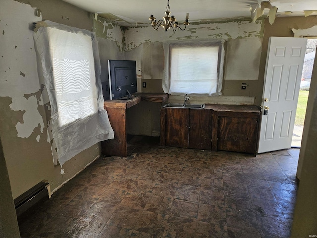 kitchen featuring dark brown cabinetry, a sink, a notable chandelier, and stone finish flooring