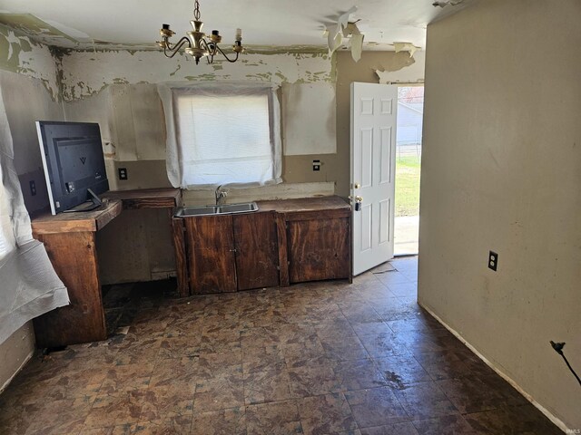 kitchen featuring a chandelier, stone finish floor, a wealth of natural light, and a sink