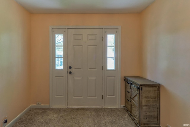 foyer entrance featuring baseboards and carpet