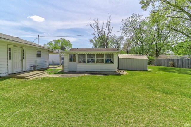back of property featuring a lawn, an outdoor structure, fence, and a gate