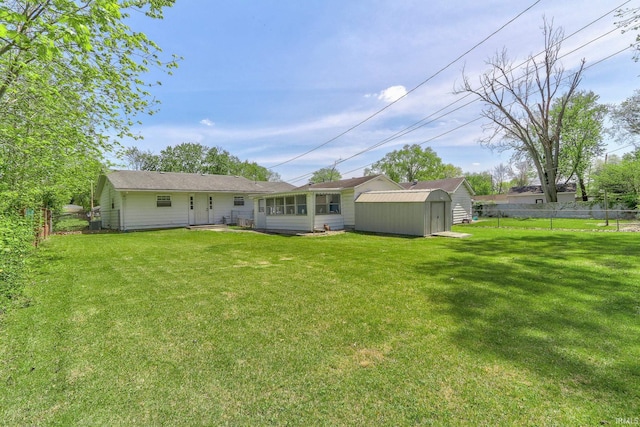 rear view of property with fence, an outbuilding, a yard, and a storage unit