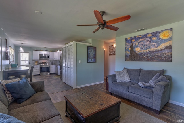 living area with dark wood-type flooring, visible vents, baseboards, and ceiling fan