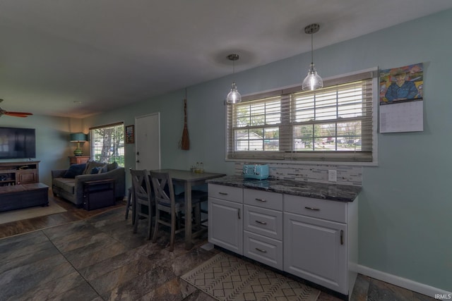interior space with stone finish flooring, baseboards, and ceiling fan