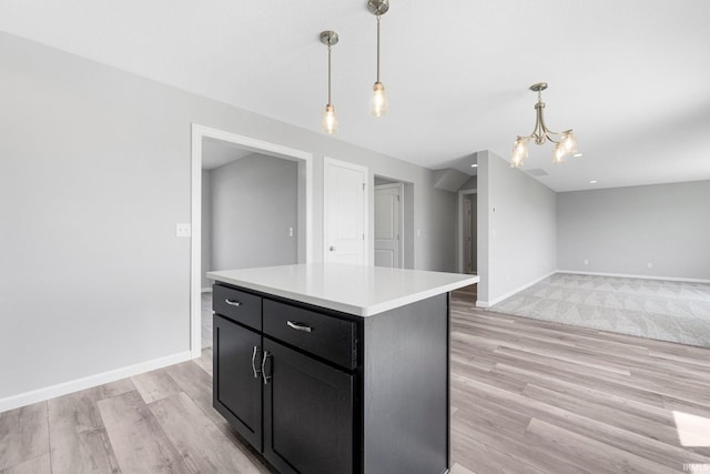 1010 Bryce Cir, Ligonier, IN 46797 - kitchen featuring light wood-type flooring, a notable chandelier, dark cabinetry, light countertops, and hanging light fixtures