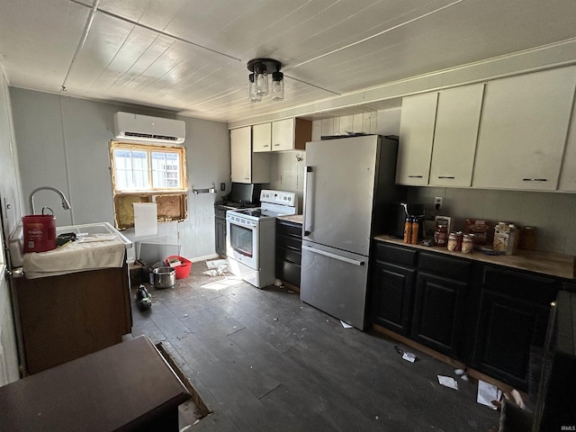 kitchen with a wall mounted air conditioner, white electric range oven, white cabinets, dark wood finished floors, and freestanding refrigerator