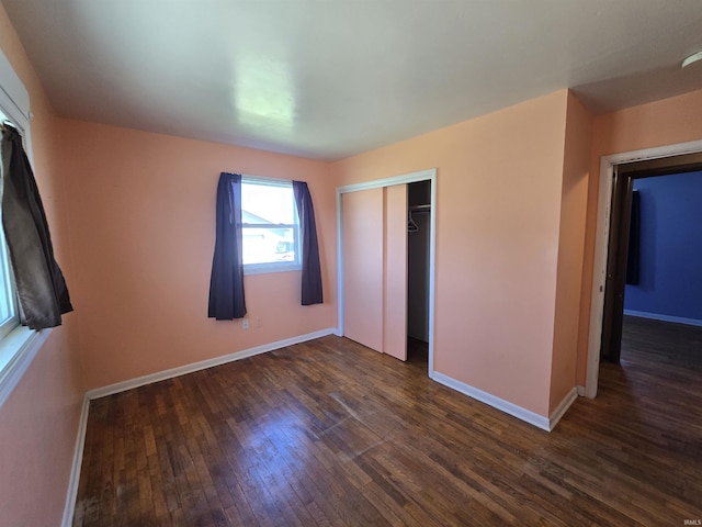 unfurnished bedroom featuring baseboards, a closet, and dark wood finished floors