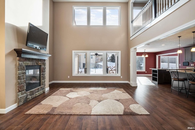 3018 Caradoza Cv, Fort Wayne, IN 46825 - living room featuring plenty of natural light, a fireplace, a high ceiling, and dark wood-type flooring
