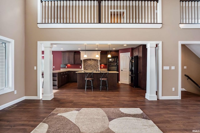 3018 Caradoza Cv, Fort Wayne, IN 46825 - living area with baseboards, dark wood-style flooring, and decorative columns