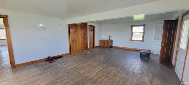 empty room with dark wood-type flooring and baseboards