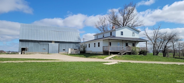 view of front of property featuring a porch, a front lawn, an outdoor structure, and a barn