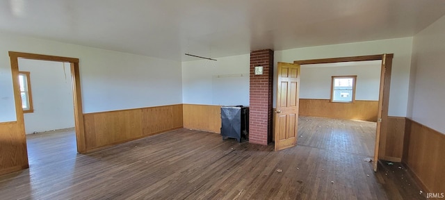 unfurnished room featuring dark wood finished floors, a wainscoted wall, and wood walls