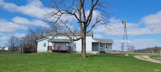 rear view of property with a lawn and roof with shingles