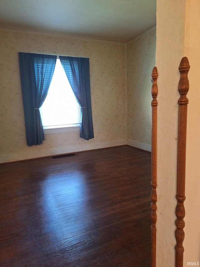 empty room featuring visible vents, baseboards, and wood finished floors