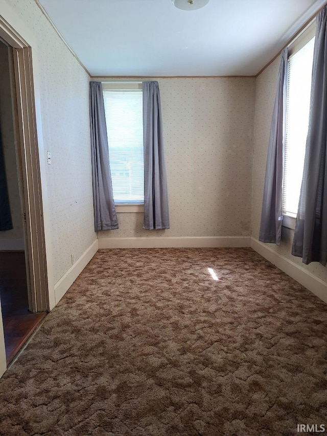 carpeted spare room with wallpapered walls and plenty of natural light