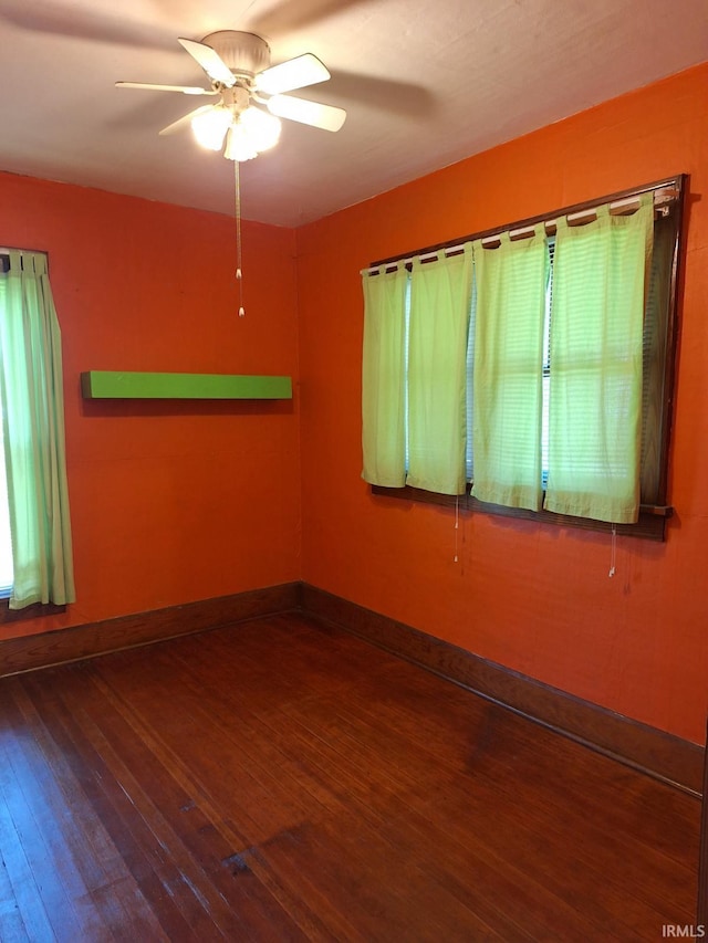 spare room featuring hardwood / wood-style floors, a ceiling fan, and baseboards