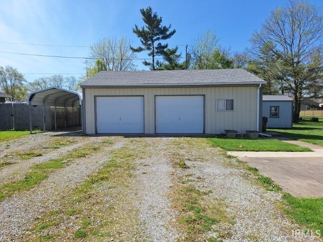 detached garage featuring driveway and fence