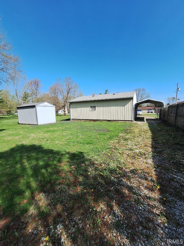 view of yard with a carport, an outbuilding, and fence