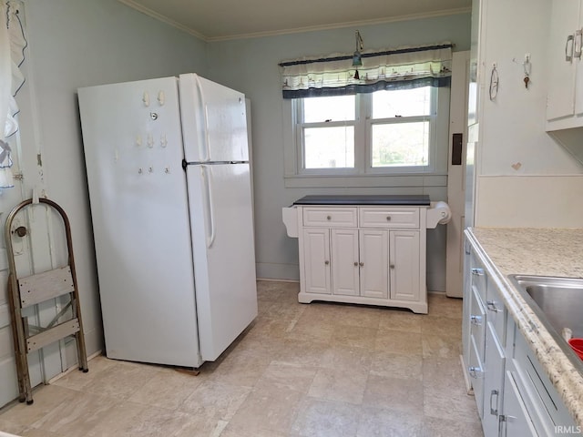 kitchen with ornamental molding, a sink, white cabinetry, and freestanding refrigerator