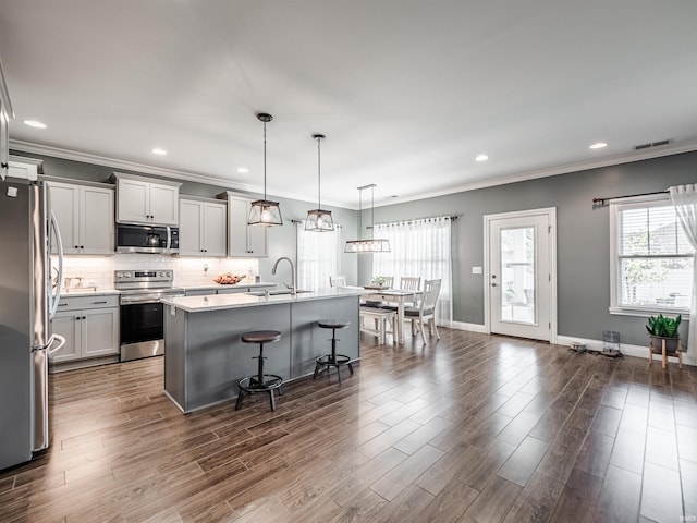 kitchen with appliances with stainless steel finishes, a breakfast bar, visible vents, and plenty of natural light