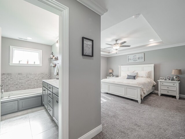 bedroom featuring a tray ceiling, visible vents, ornamental molding, and connected bathroom
