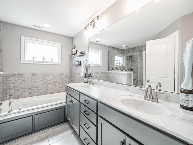 bathroom featuring a bath, a sink, visible vents, and a stall shower