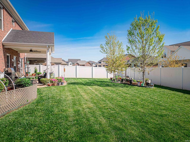 view of yard featuring a vegetable garden, a fenced backyard, a ceiling fan, and a residential view