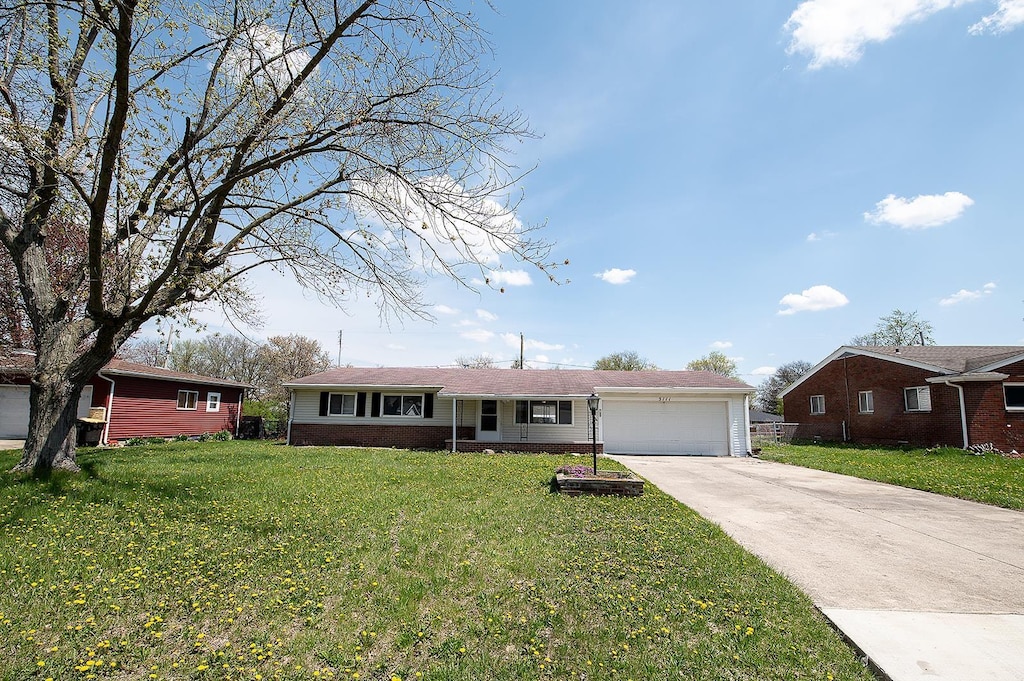 ranch-style home with concrete driveway, an attached garage, brick siding, and a front lawn