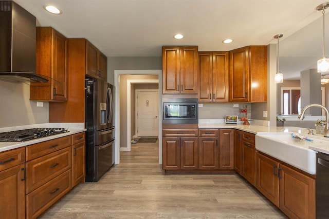 kitchen featuring built in microwave, stainless steel fridge with ice dispenser, gas cooktop, a sink, and wall chimney exhaust hood