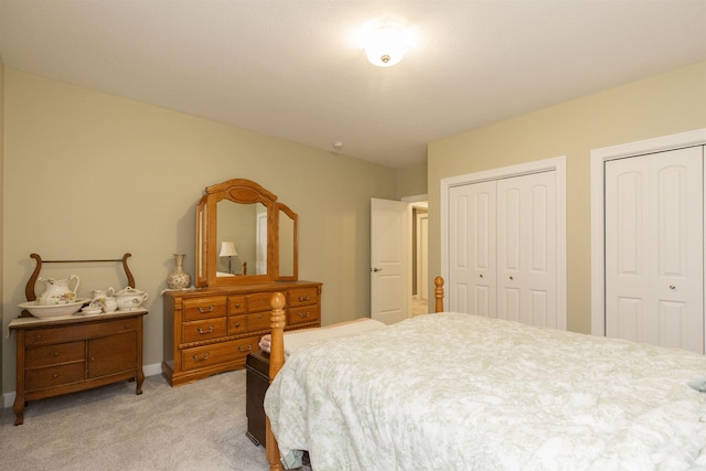 bedroom featuring multiple closets, baseboards, and light colored carpet